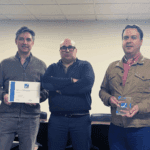 Três homens a posar para foto, dois com um prémio na mão